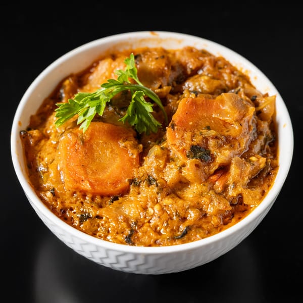 A white bowl filled with a rich orange Haitian stew, garnished with fresh parsley.